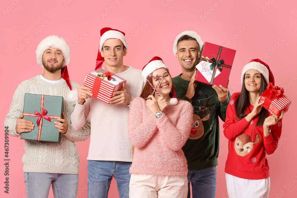 Group of friends with Christmas gifts and candy canes on color background