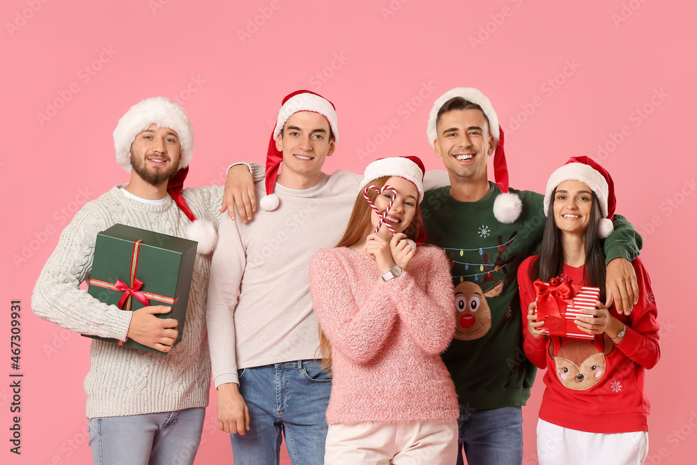 Group of friends with Christmas gifts and candy canes on color background