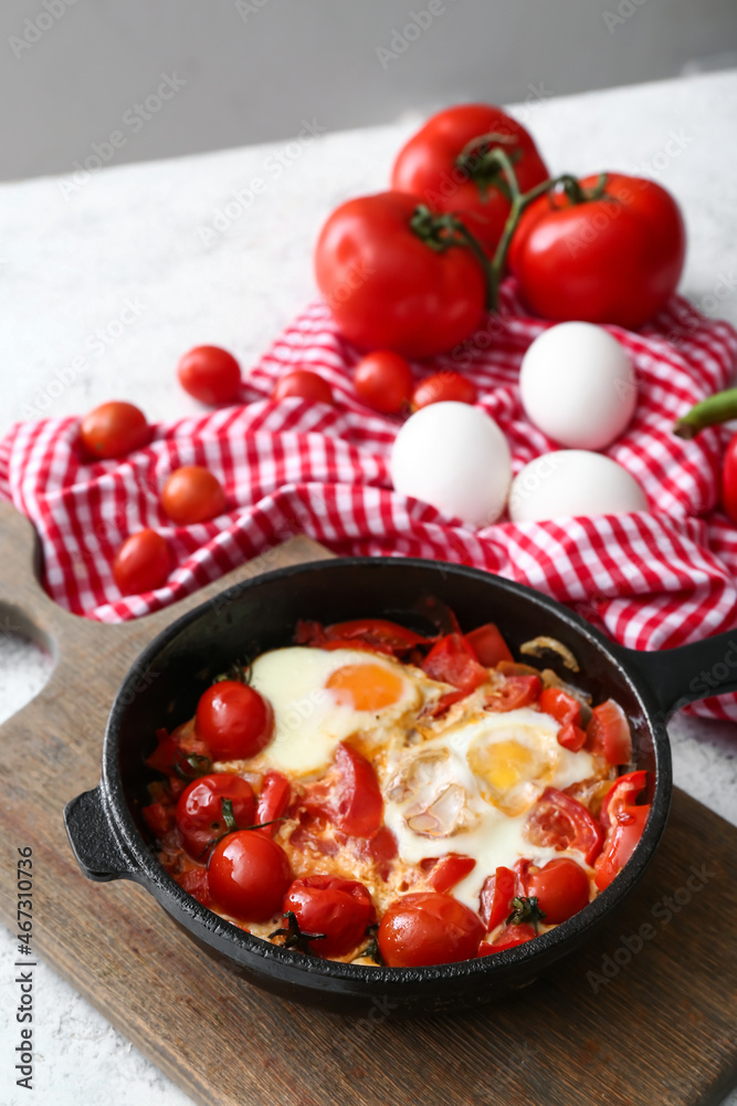 Frying pan with tasty Shakshouka on table