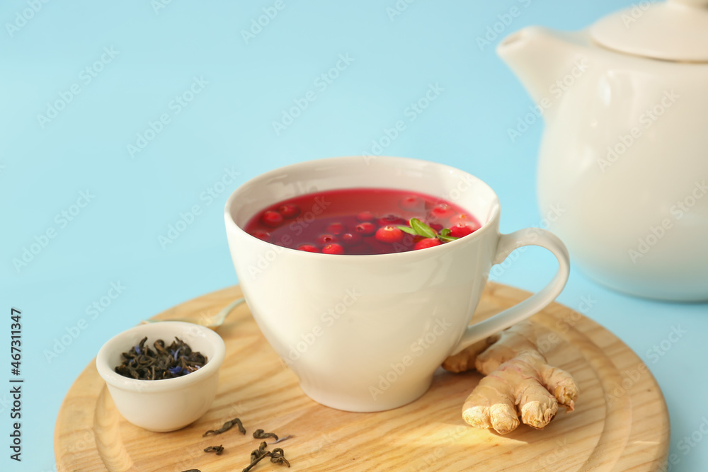 Wooden board with cup of tasty lingonberry tea on color background, closeup