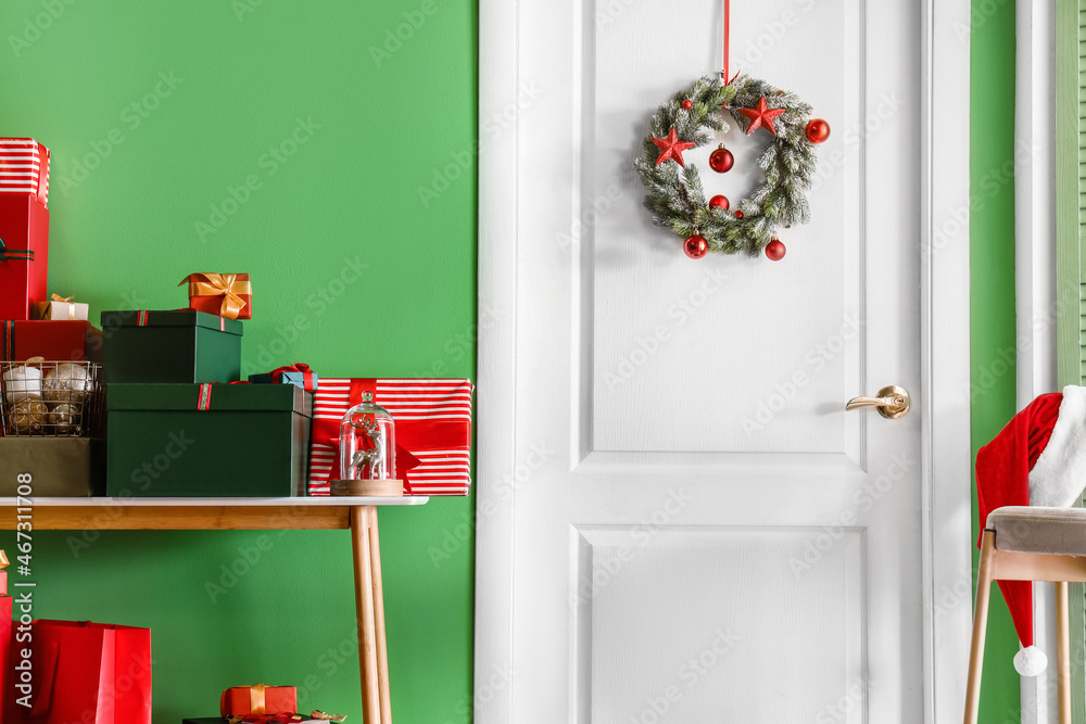 Wreath hanging on white door in room decorated for Christmas