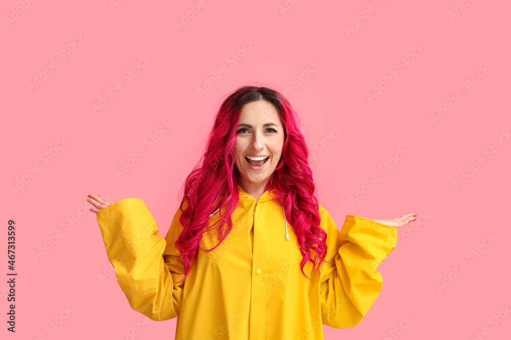 Beautiful woman with bright hair wearing raincoat on color background