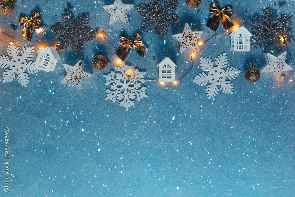 Christmas blue background with a garland of snowflakes and wooden houses free space for text.