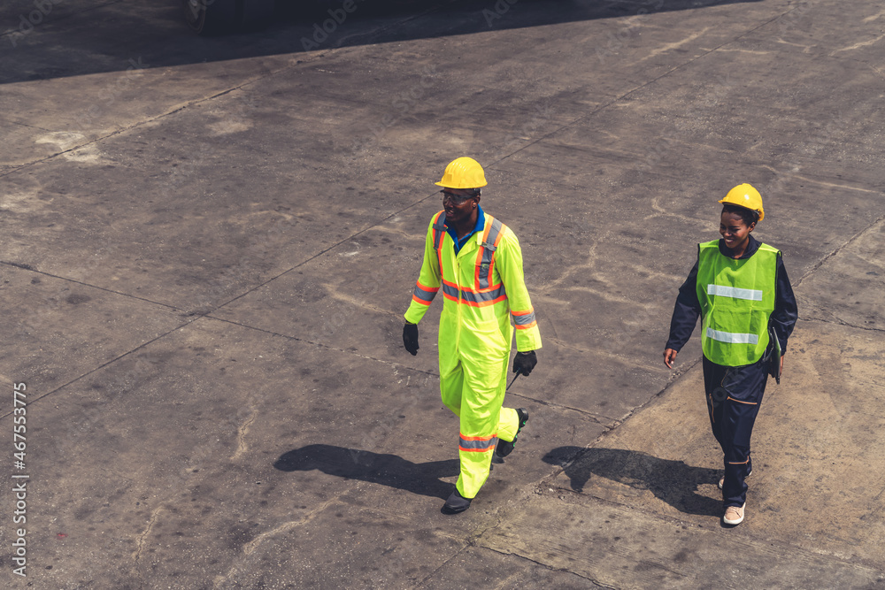 Industrial worker works with co-worker at overseas shipping container yard . Logistics supply chain 