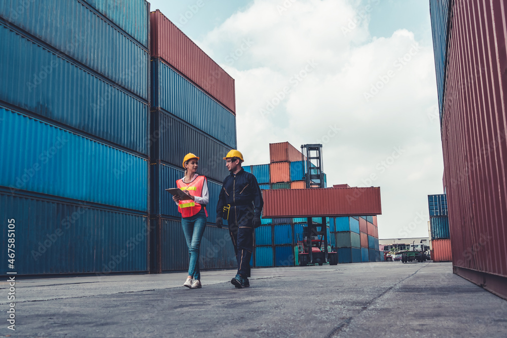 Industrial worker works with co-worker at overseas shipping container yard . Logistics supply chain 