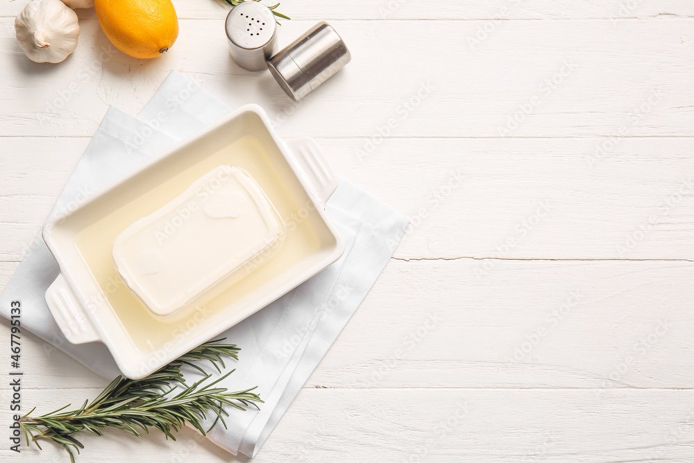 Baking dish with feta cheese on light wooden background