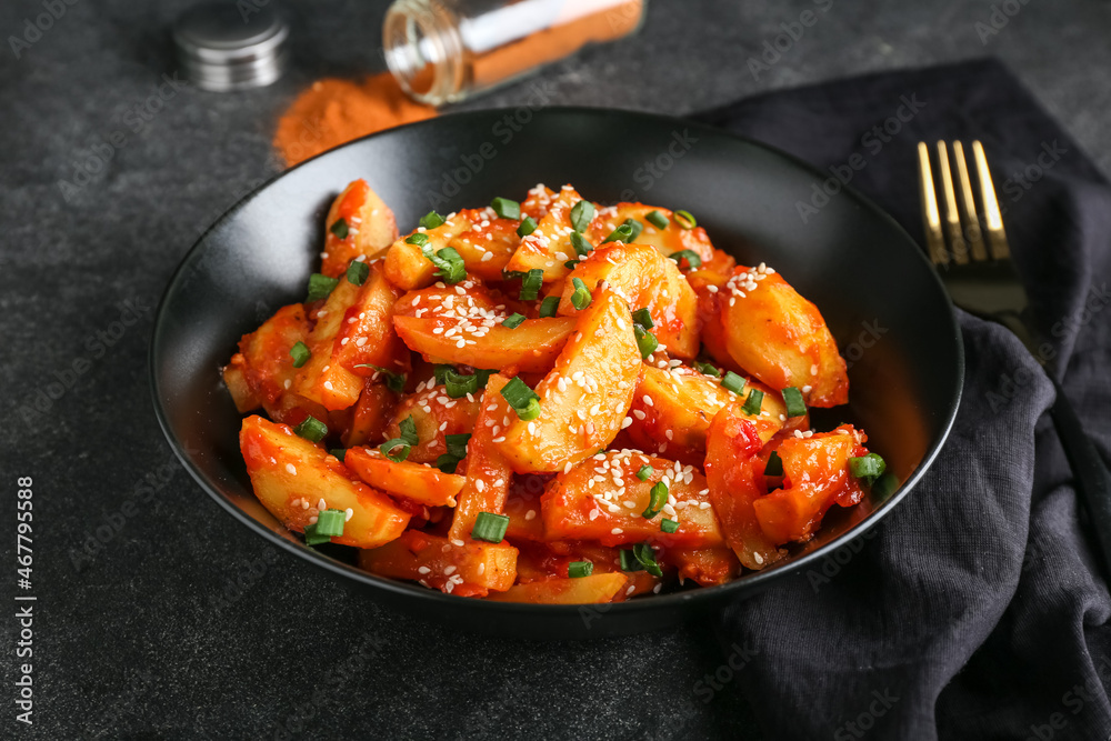 Plate with honey chilli potato on dark background