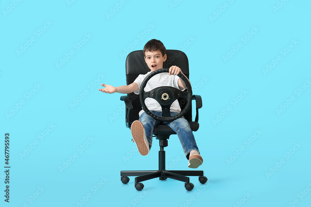 Little boy with steering wheel sitting in chair on color background