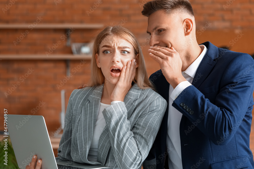 Male and female colleagues gossiping in office