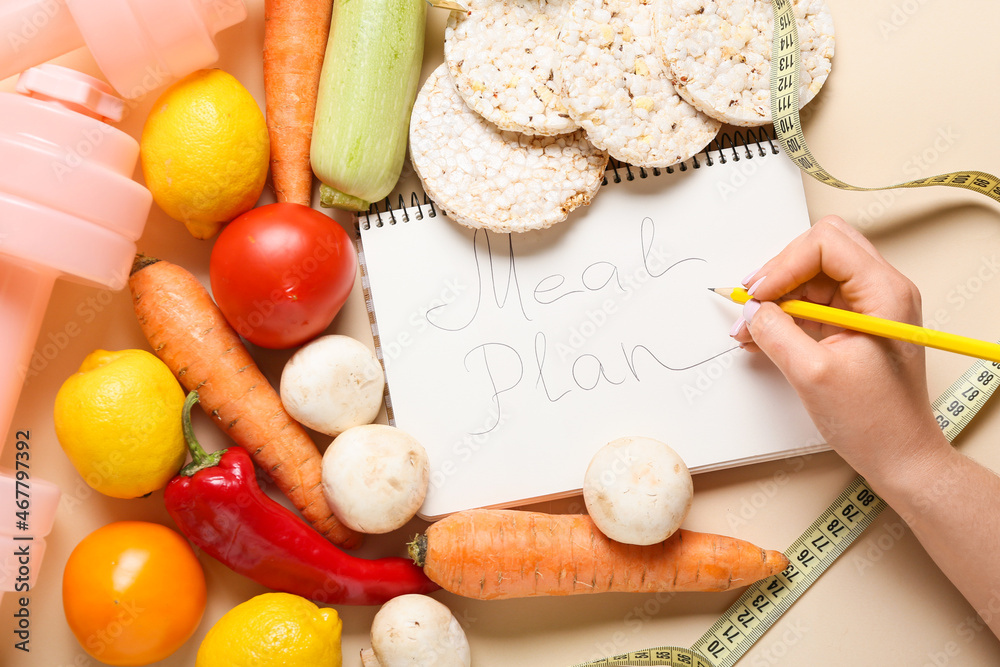 Woman making meal plan on color background