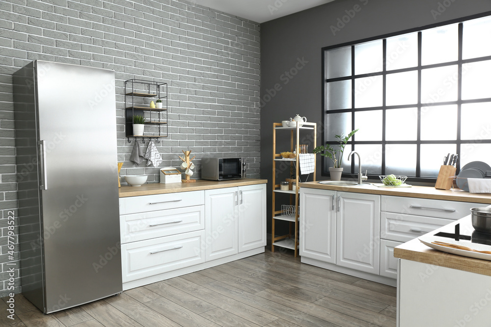 Interior of modern kitchen with fridge and white counters