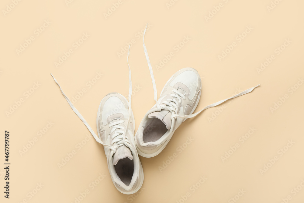 Sportive shoes with untied laces on color background