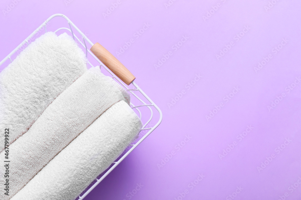 Basket with clean towels on lilac background, closeup