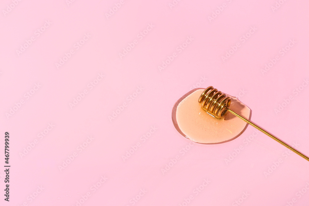 Dipper with sweet honey on pink background, closeup