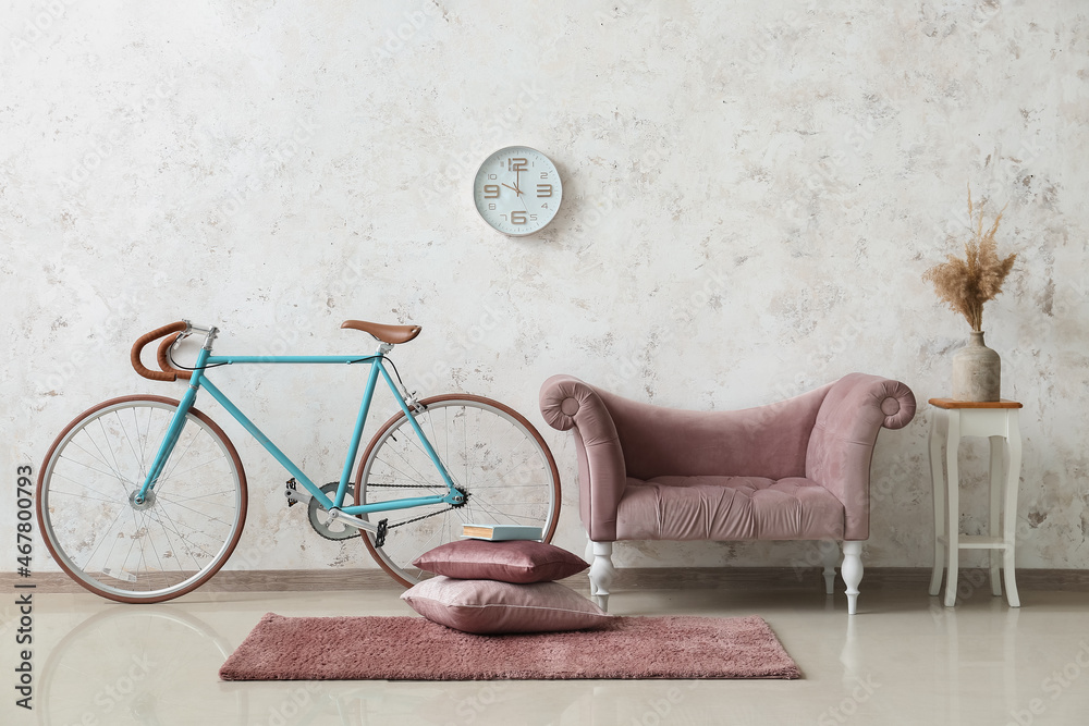 Interior of light living room with pink sofa and bicycle