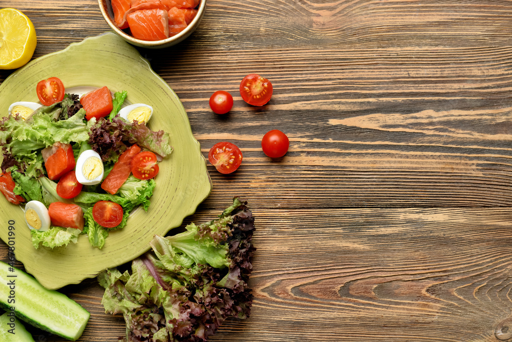 Tasty salad with salmon and fresh vegetables in plate on wooden background