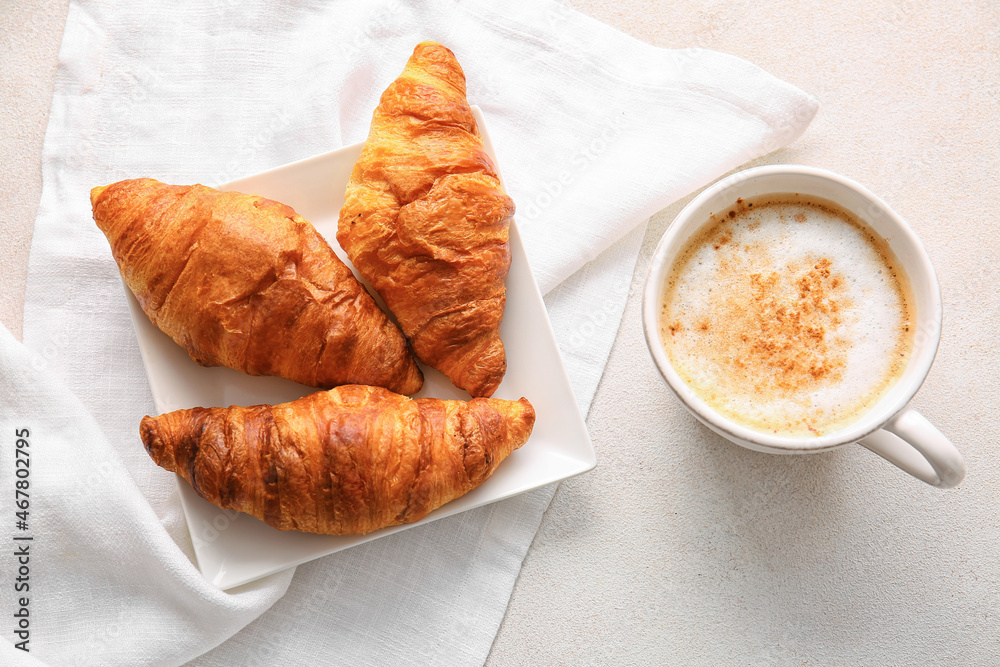 Plate with delicious croissants and cup of coffee on white background