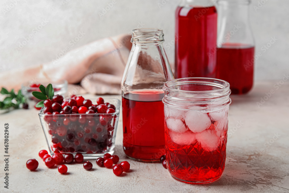 Bottle and glass with healthy cranberry juice on light background