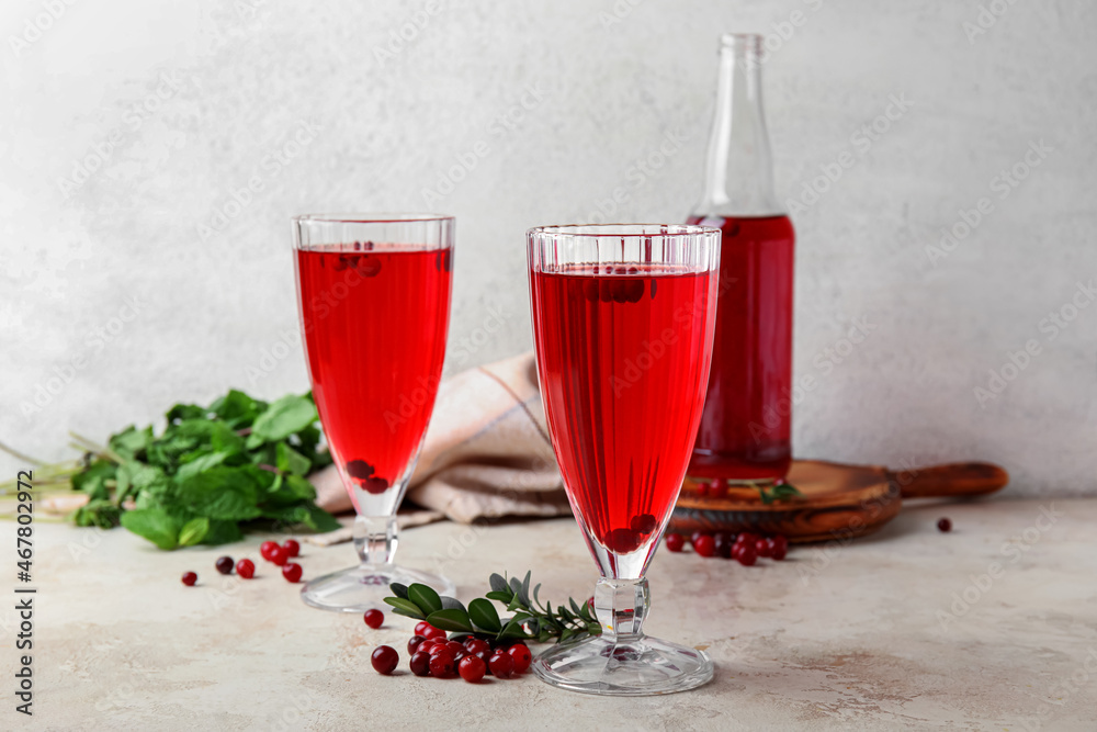 Glasses with healthy cranberry juice on light background