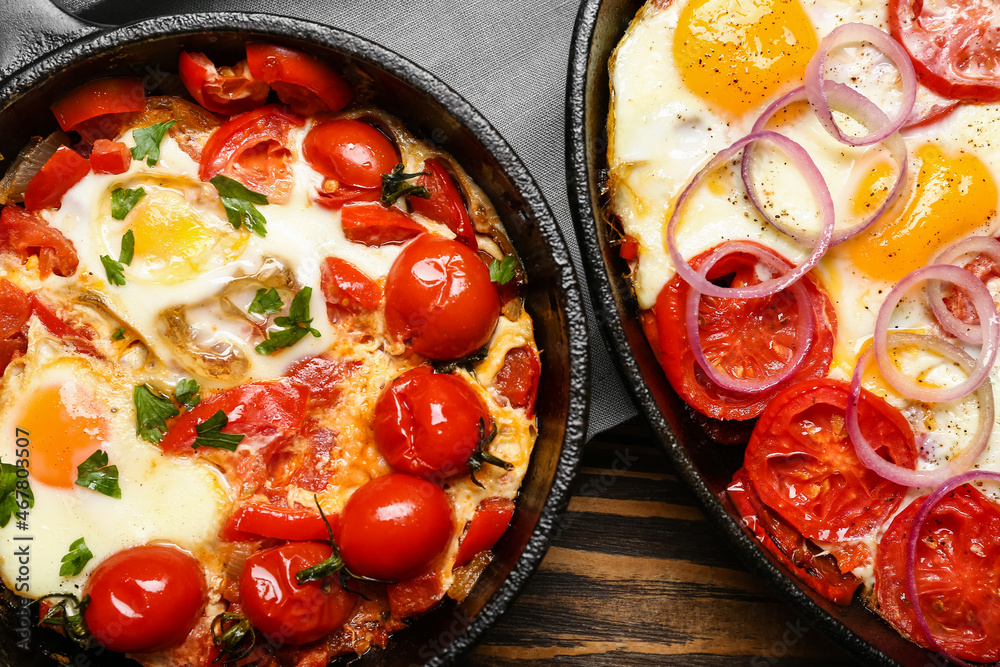 Baking dish and frying pan with tasty Shakshouka on wooden background, closeup