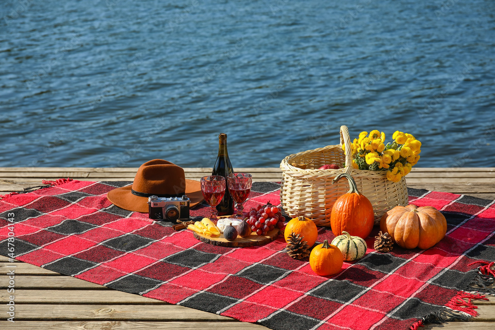 Tasty food with wine for romantic picnic near river on autumn day