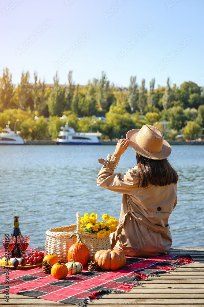 Young woman having romantic picnic near river