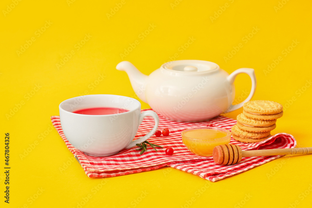 Cup of tasty lingonberry tea, honey and cookies on color background