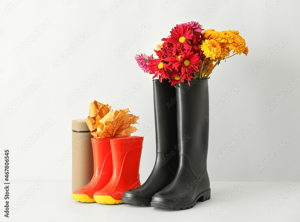 Rubber boots, flowers, thermos and leaves on white background