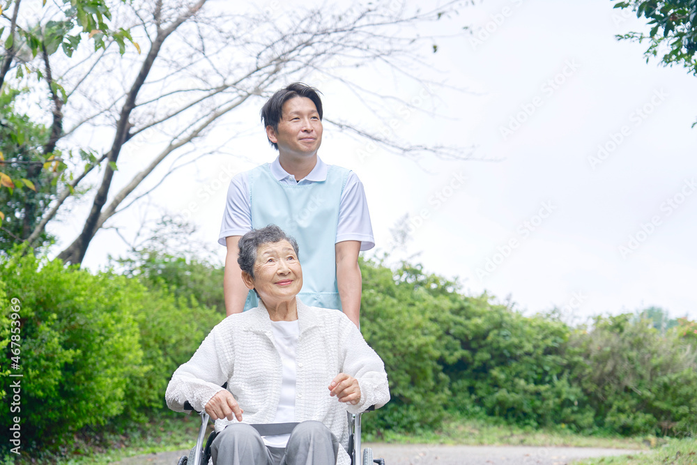 介護士と車椅子に乗る高齢者　屋外