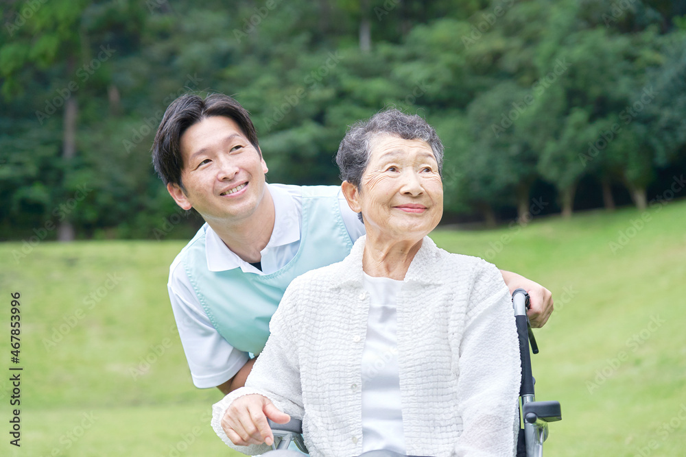 介護士と車椅子に乗る高齢者　屋外