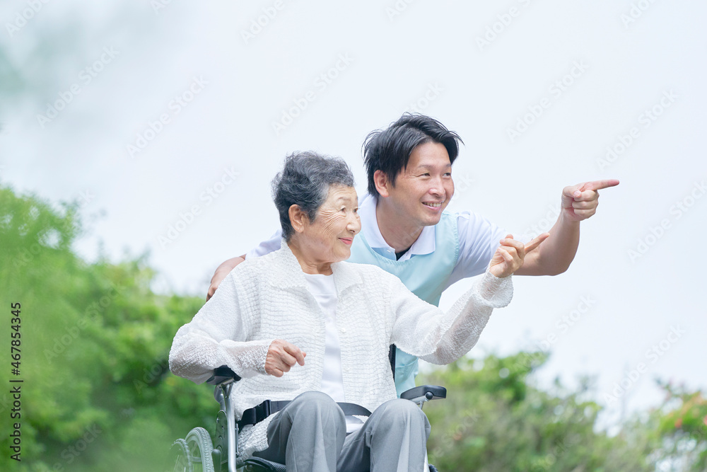 介護士と車椅子に乗る高齢者　屋外