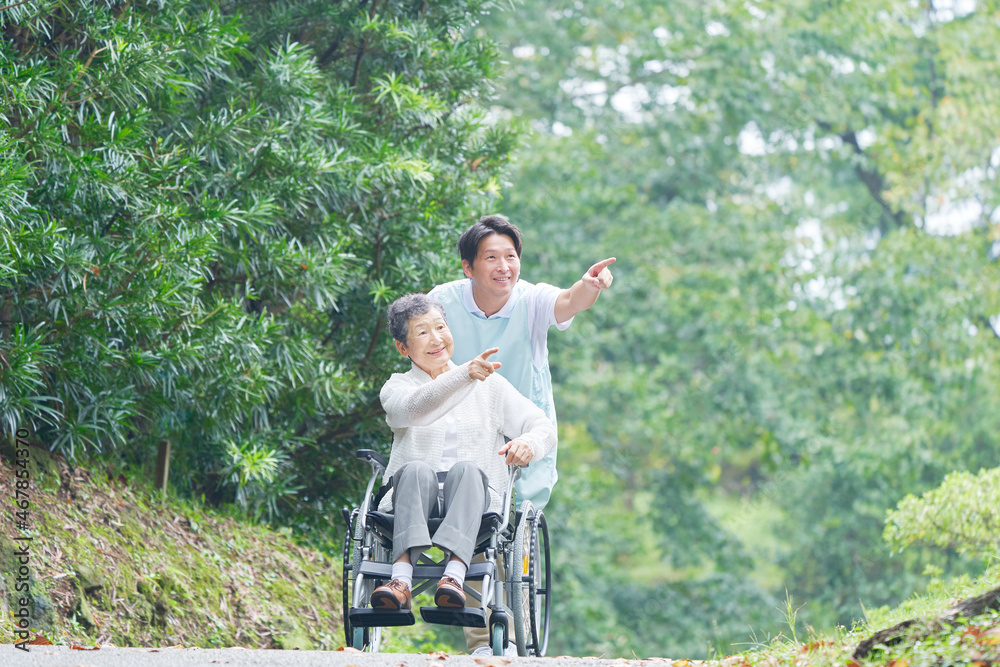 介護士と車椅子に乗る高齢者　屋外