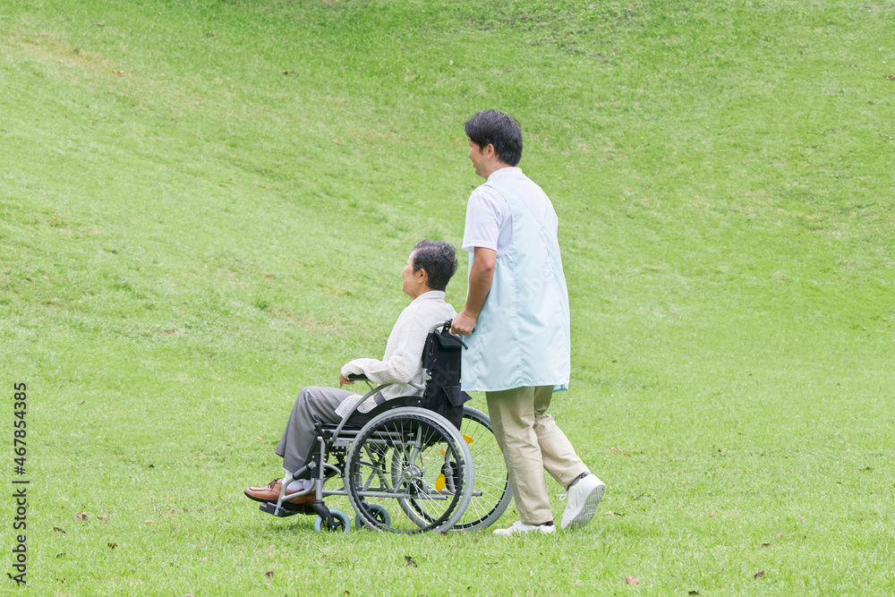 介護士と車椅子に乗る高齢者　屋外