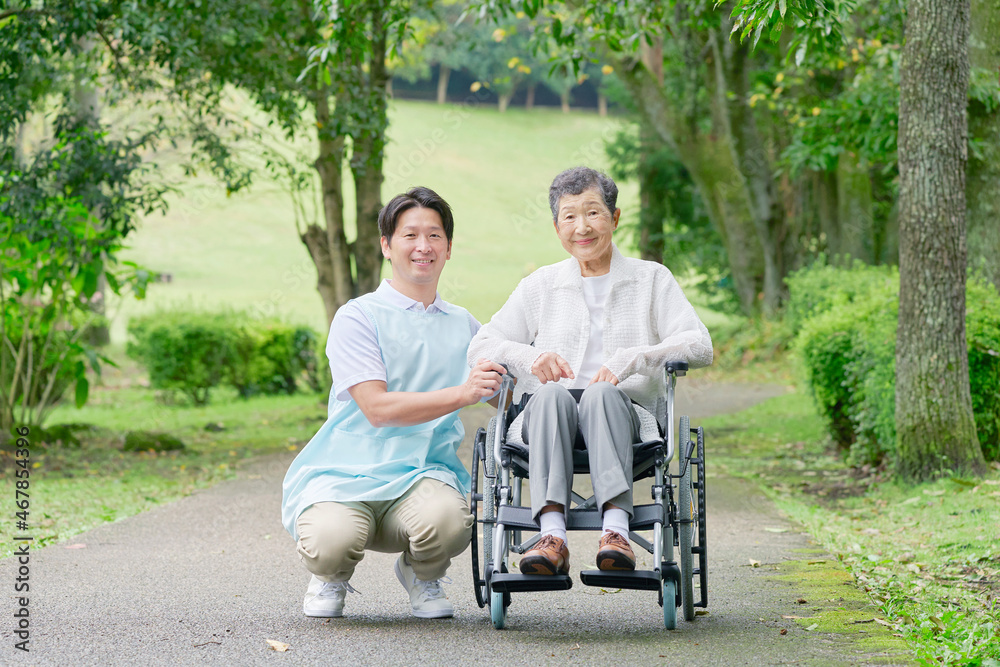 介護士と車椅子に乗る高齢者　屋外