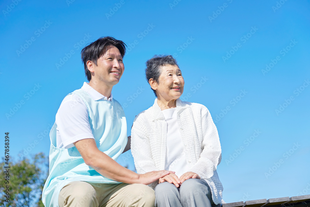 介護士と車椅子に乗る高齢者　屋外