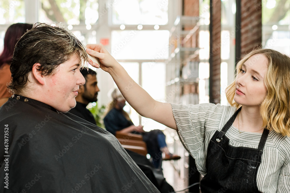 Hairstylist trimming hair of the customer in a beauty salon