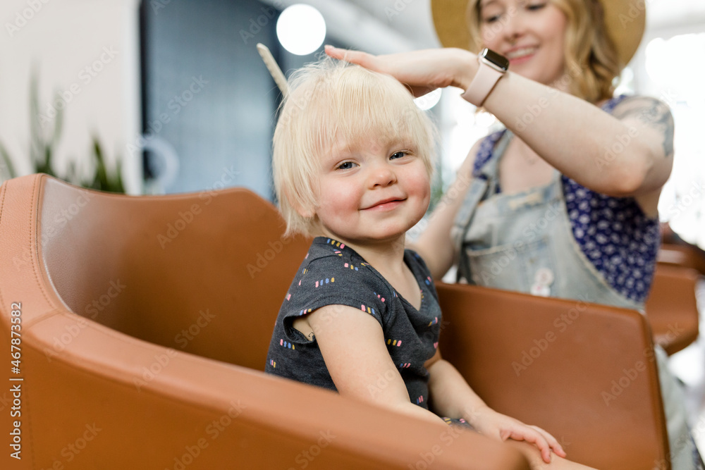 Hairstylist giving a haircut to an adorable blond kid