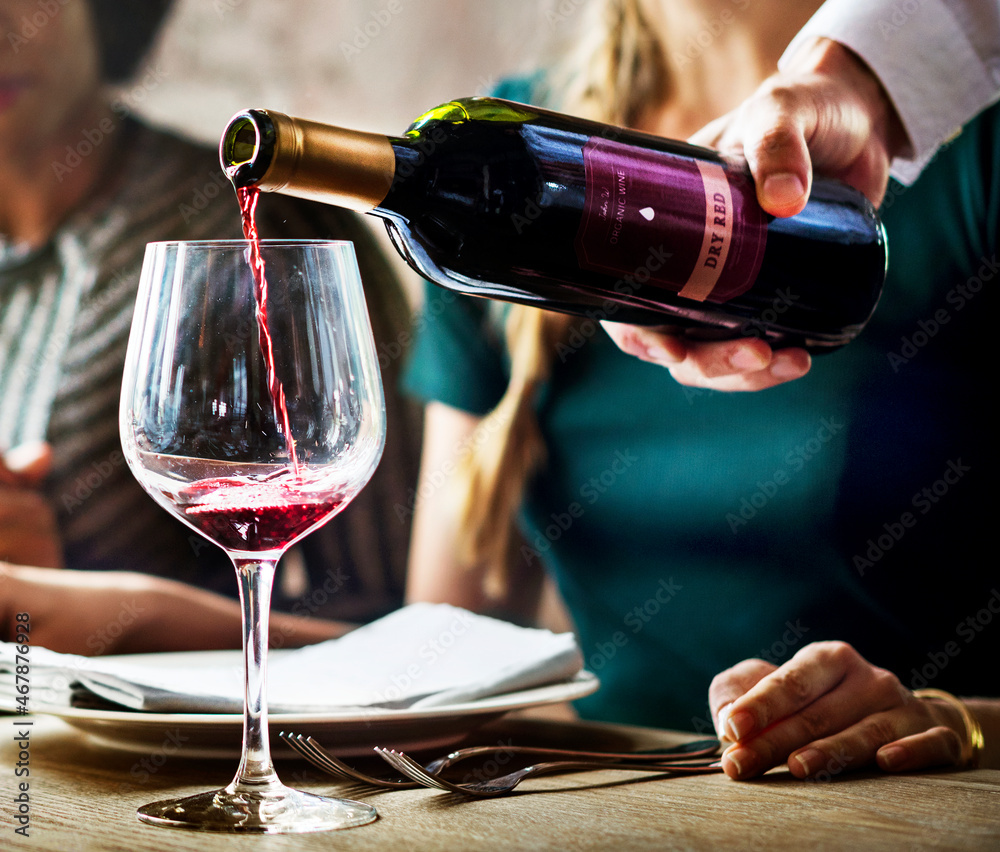 Waiter Poring Serving Red Wine to Customers in a Restaurant