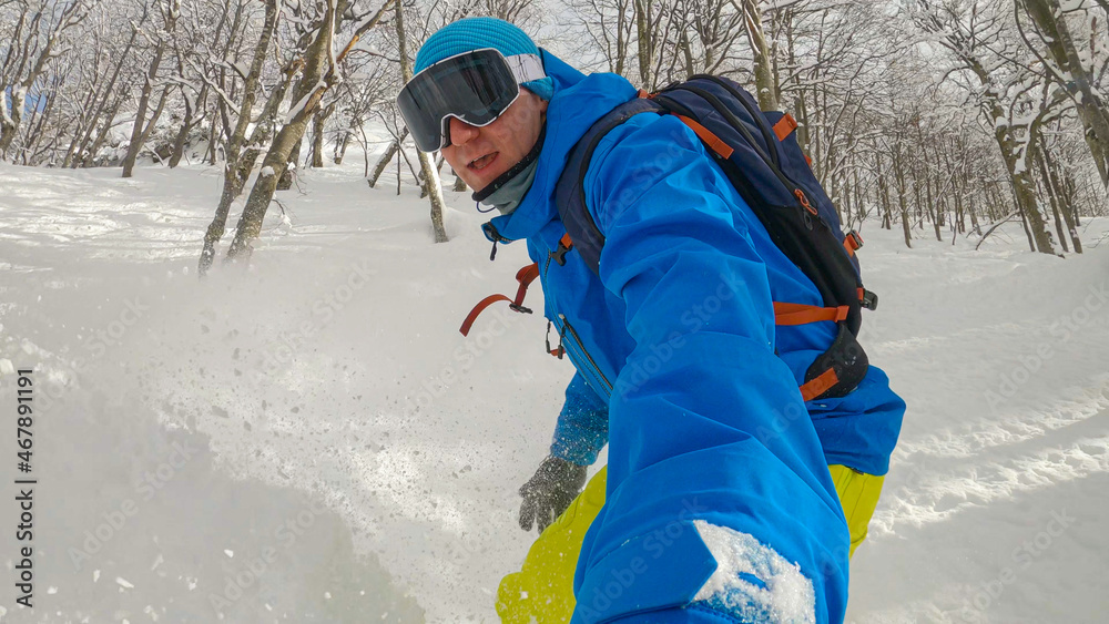 SELFIE：活跃的男性游客在树和碎雪之间滑雪。