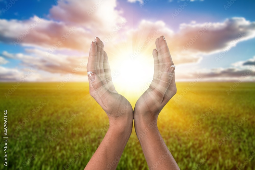 young woman raising hands praying at sunset light