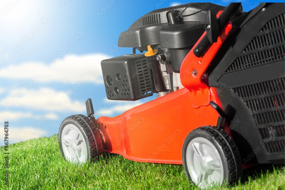 Lawn mover on green grass in modern garden. Cutting lawns.