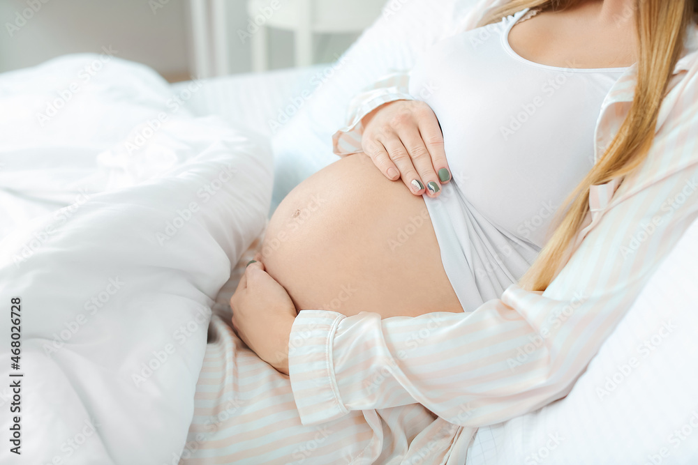 Young pregnant woman lying in bed, closeup