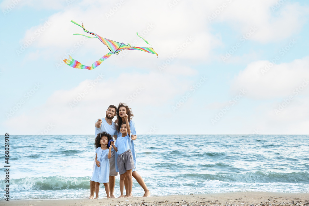 Happy family flying kite on sea beach