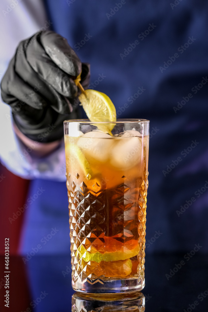 Female bartender decorating glass of tasty Cuba Libre cocktail on table in bar