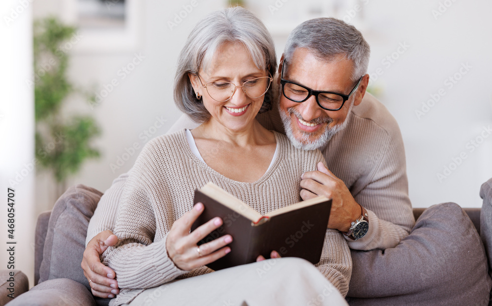 Happy smiling senior family couple in love reading book together at home