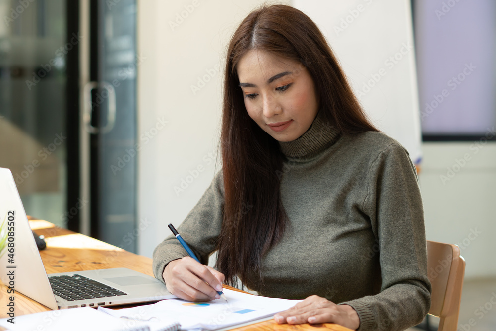 Asian businesswoman checking document report at co-working place.