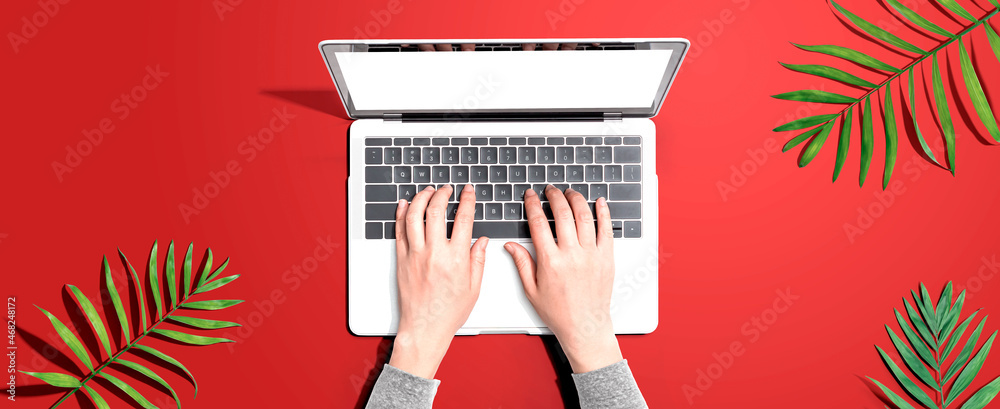 Person using a laptop computer with tropical leaves from above