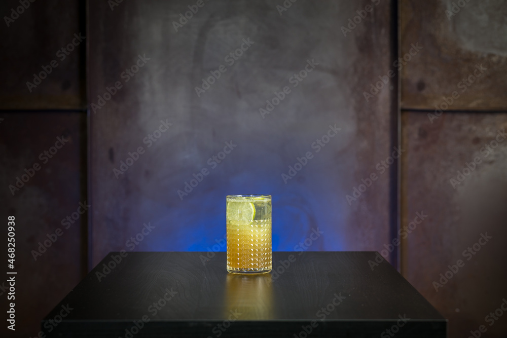 glass of cocktail with crushed ice on woden table on blue background 