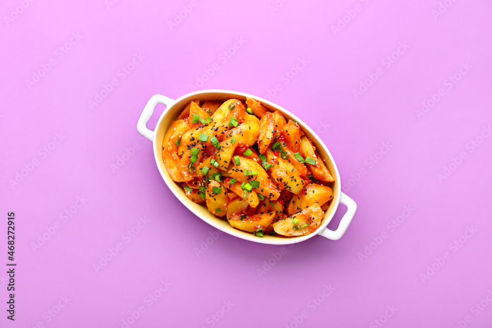 Baking dish with honey chilli potato on color background