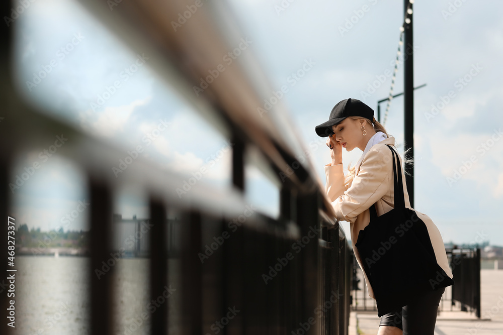 桥上戴棒球帽的沉思女子